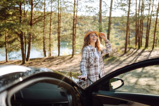 Young woman traveler Young woman standing near the car in sunny day