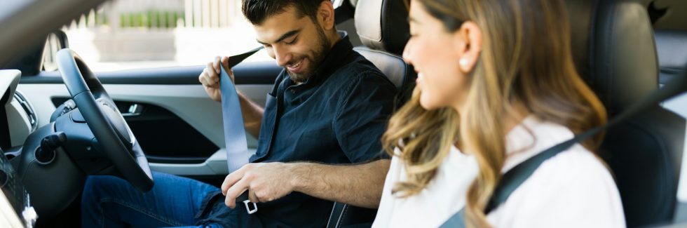 young couple in car, putting on seatbelt